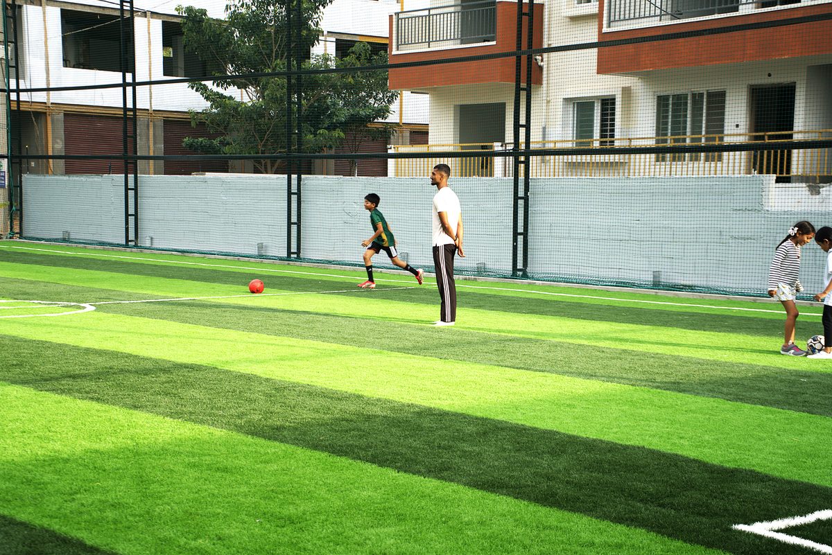 Kids playing football with a coach on the turf